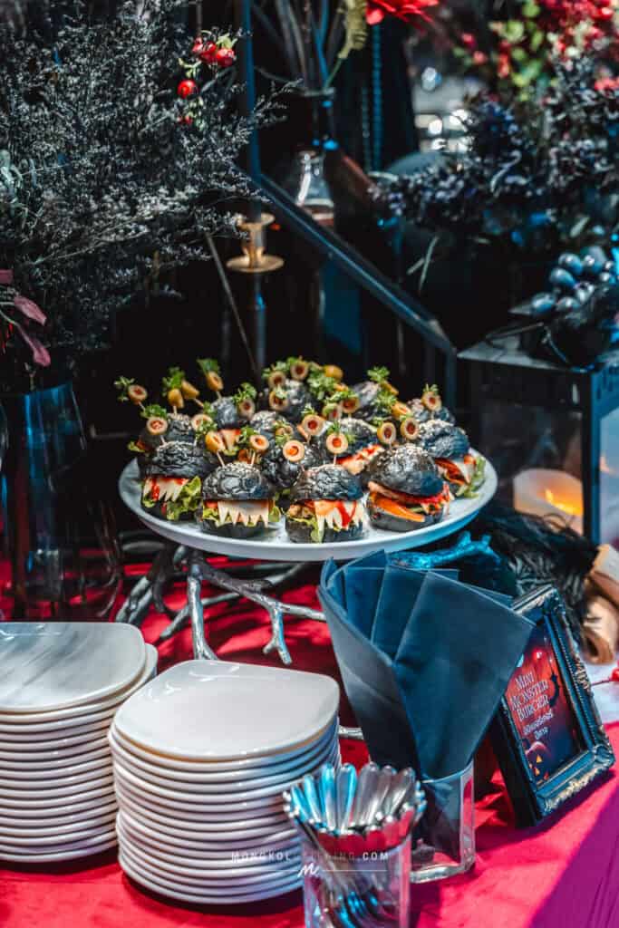 Delicious black burger sliders displayed on a silver stand at a catered event in Thailand.
