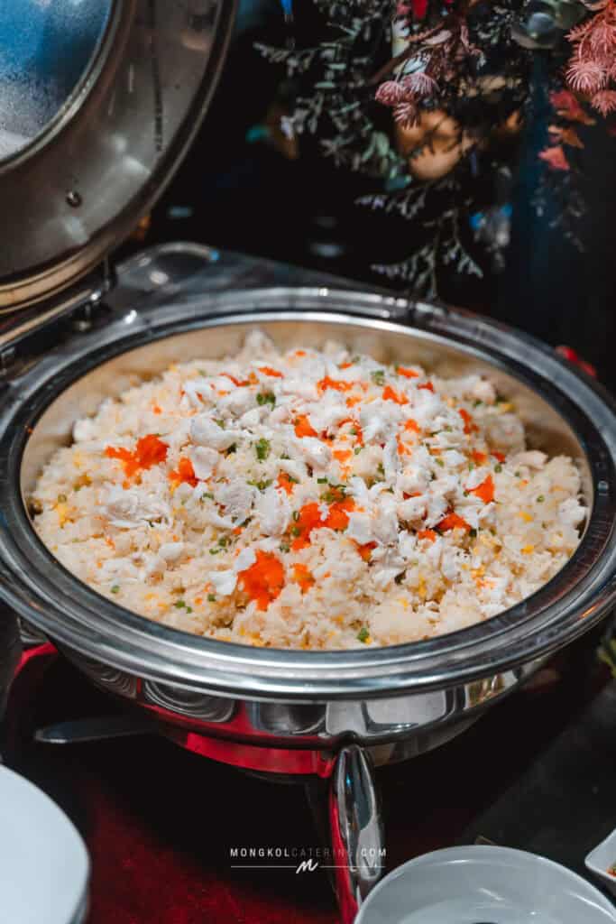 Steamed rice with shredded chicken, carrots, and green onions in a serving dish at Mongkol Catering, Thailand.