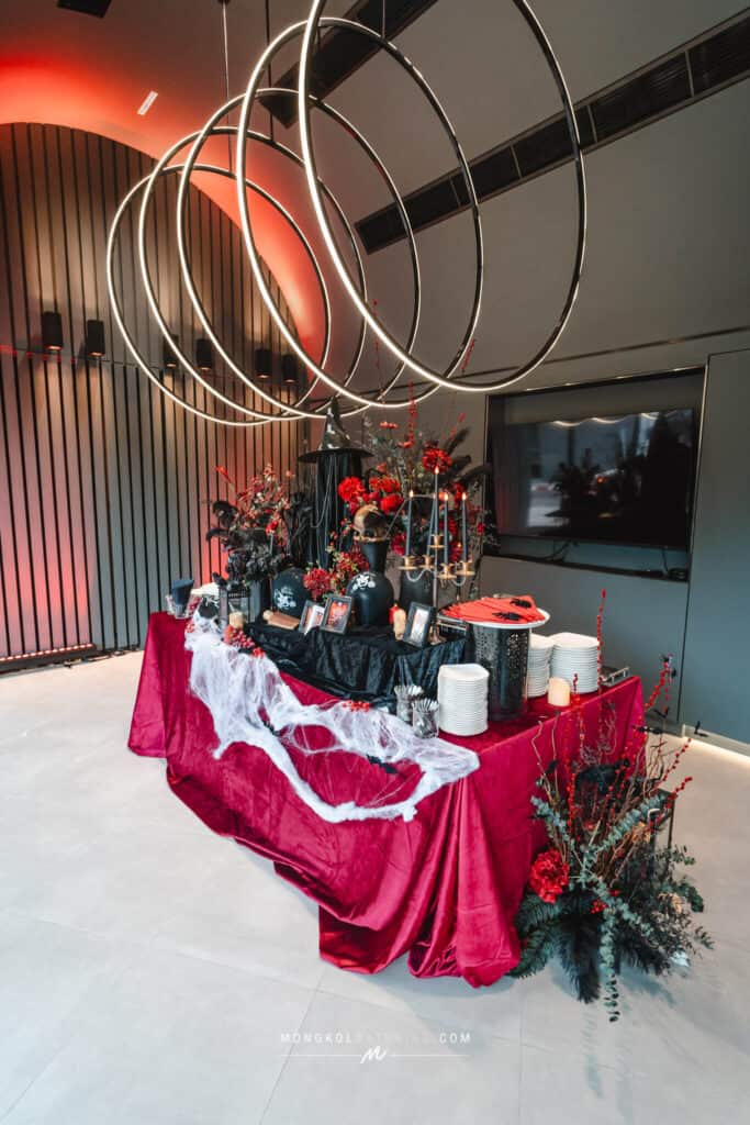 Elegant event buffet table with Halloween decor in Thailand, featuring flowers and gothic accents.