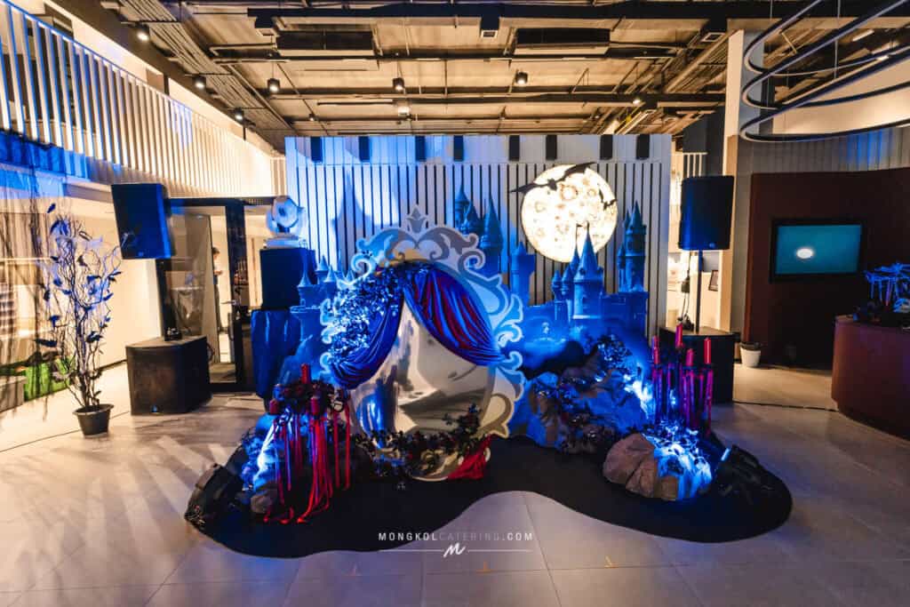 Vibrant themed party setup with castle decorations, full of blue and red accents, inside a modern event space in Thailand.