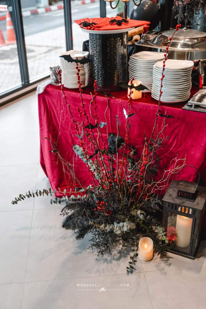 Festive Halloween-themed buffet setup with plates, candles, and spooky decorations in Thailand.