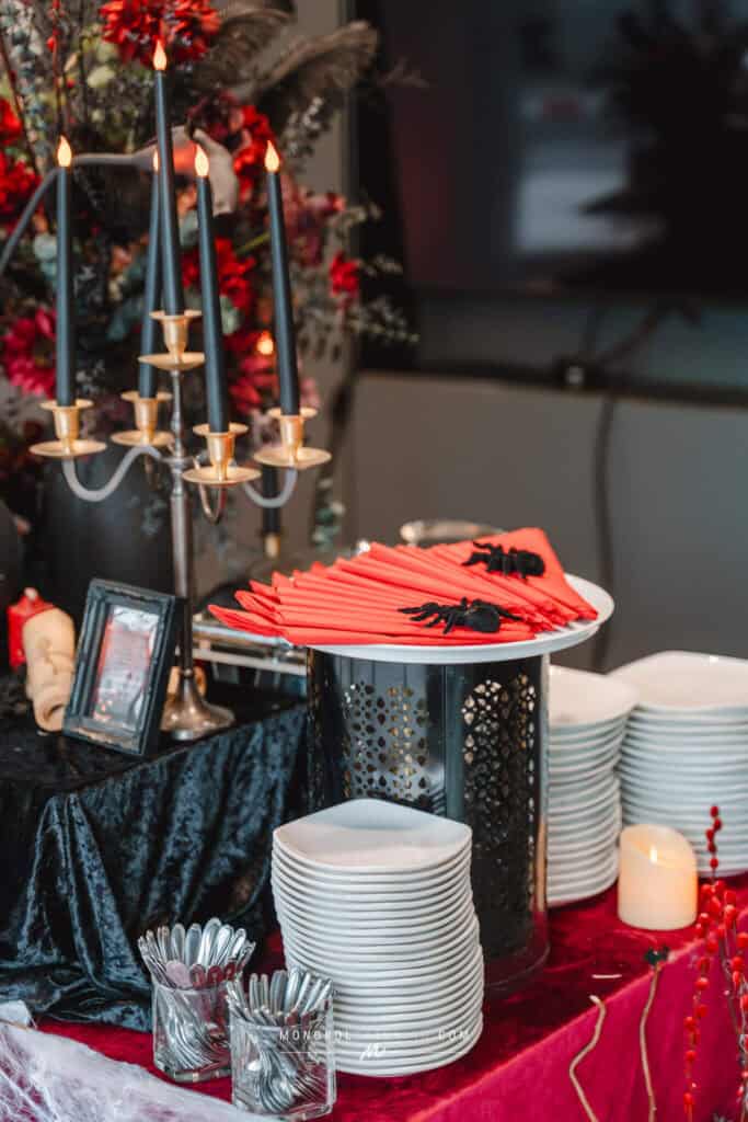 Black candles and red napkins with spider decorations at a festive event in Thailand.