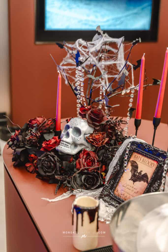 Spooky Halloween-themed flower arrangement with skull, bats, roses, candles, and cobwebs for event decoration in Thailand.