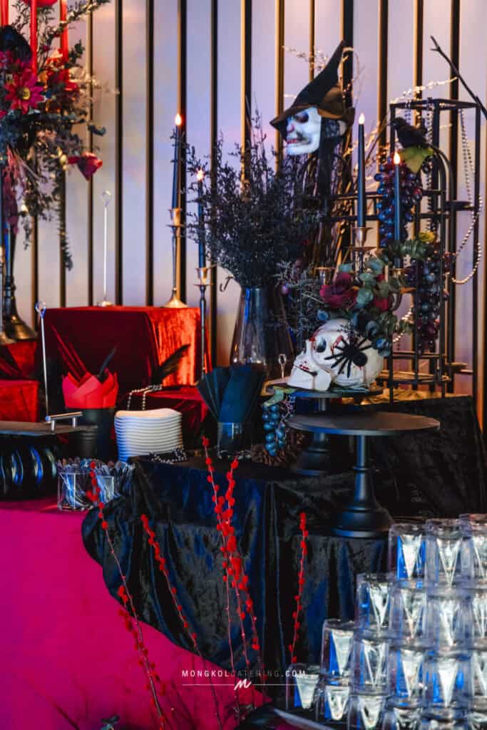 Spooky Halloween themed Halloween party setup with skull decorations, candles, and dark floral arrangements in Thailand.