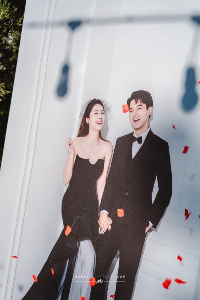 Vibrant wedding photo of a happy couple in black formal attire outdoors in Thailand.