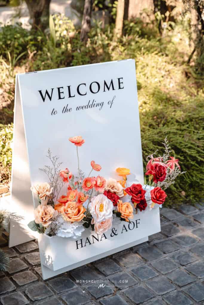 Elegant wedding welcome sign with floral arrangements in Thailand.