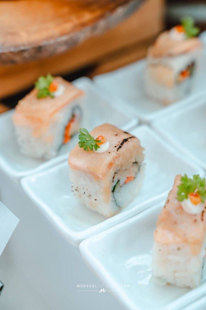 Freshly made sushi rolls with salmon, cucumber, and avocado, garnished with herbs and sauce.
