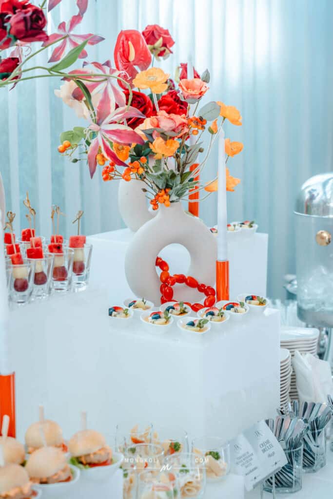 Colorful floral centerpiece with desserts at a catered event in Thailand.
