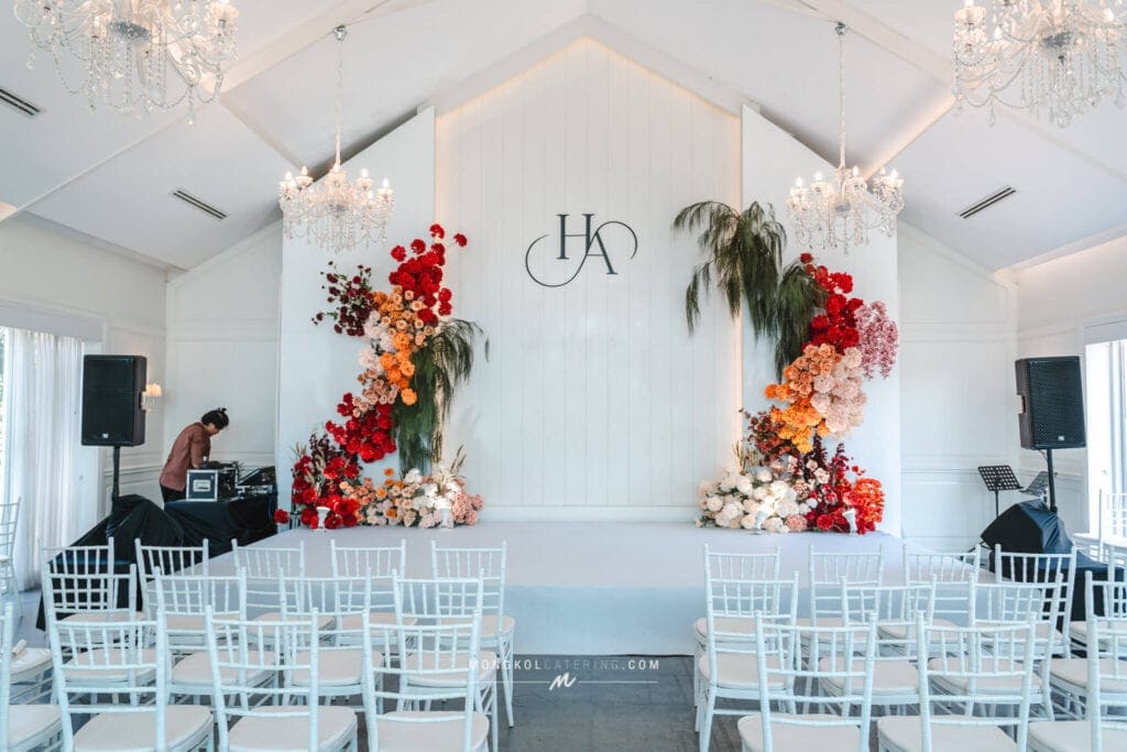 Elegant wedding stage decorated with floral arrangements and chandeliers in Thailand.