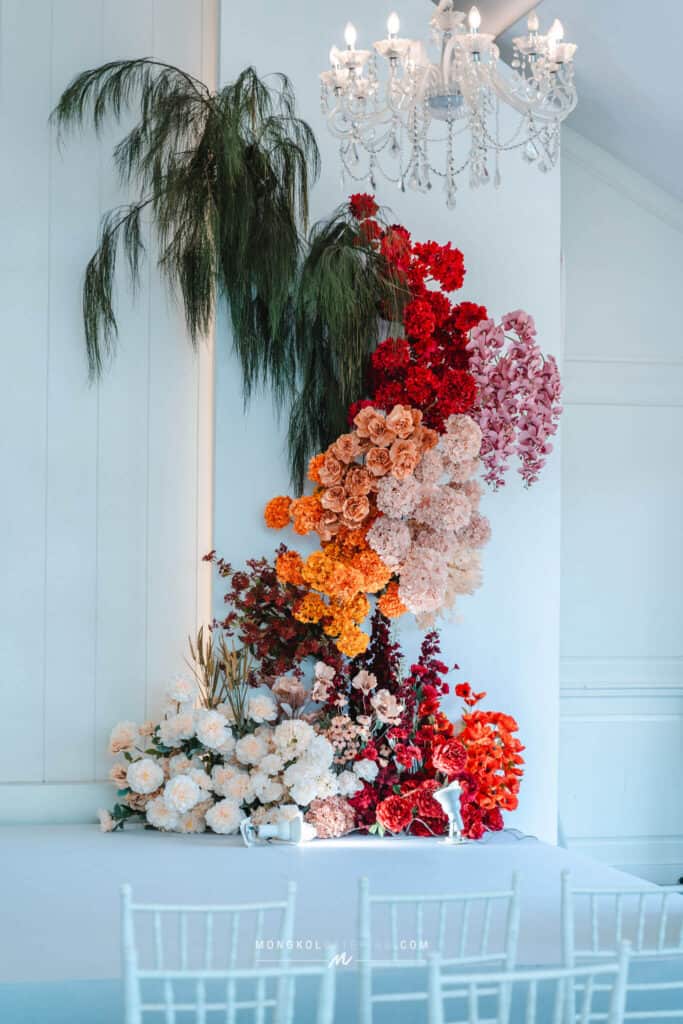 Colorful floral arrangement with pink, red, orange, and white flowers at a Thai event.