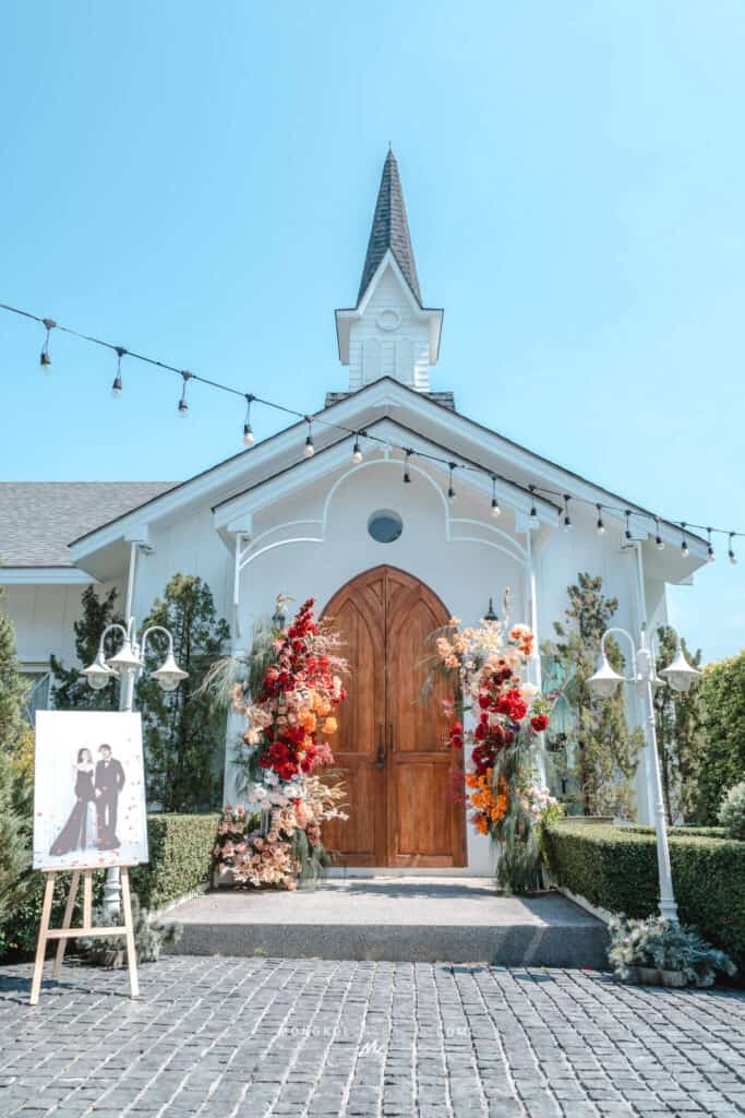 Elegant white church with wooden doors decorated with colorful flowers for wedding events in Thailand.