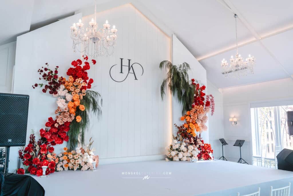 Elegant wedding stage with floral arrangements and chandeliers in Thailand.