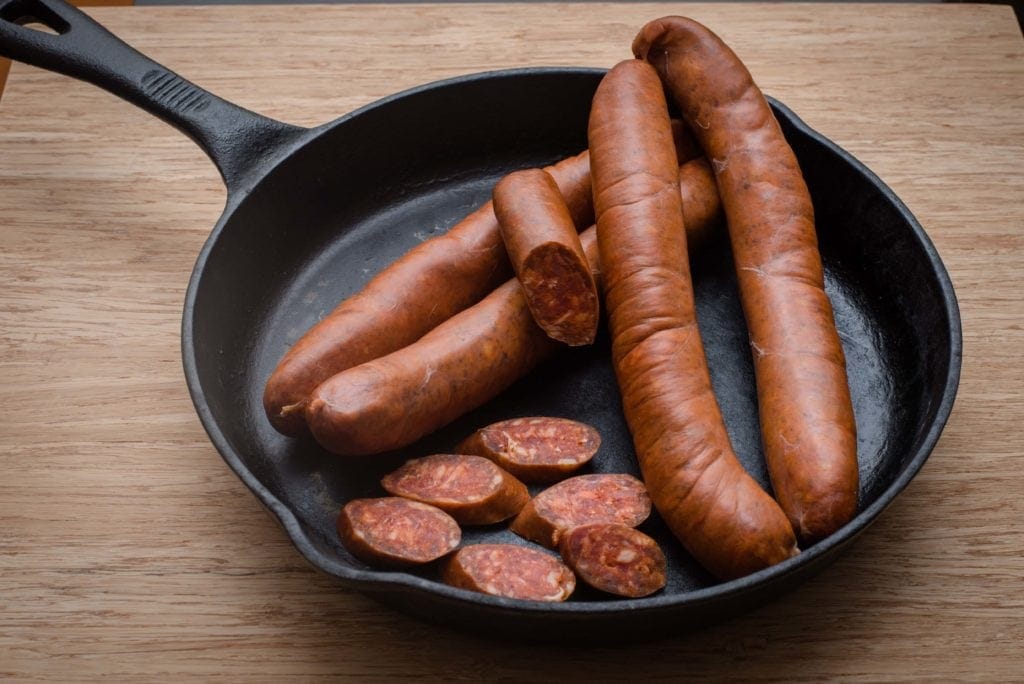 black cast iron skillet seasoned with flaxseed oil with sausages