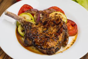 pork steak and veggies on white plate with sauce