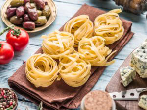 homemade pasta on cutting board surrounded by other ingredients