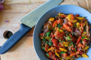 fajitas in blue bowl with knife lying on wood table beside bowl