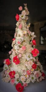 Extra-tall tiered wedding cake with hand-painted vine details and 350+ handcrafted sugar flowers at Borgo Santo Pietro in Tuscany, Italy.