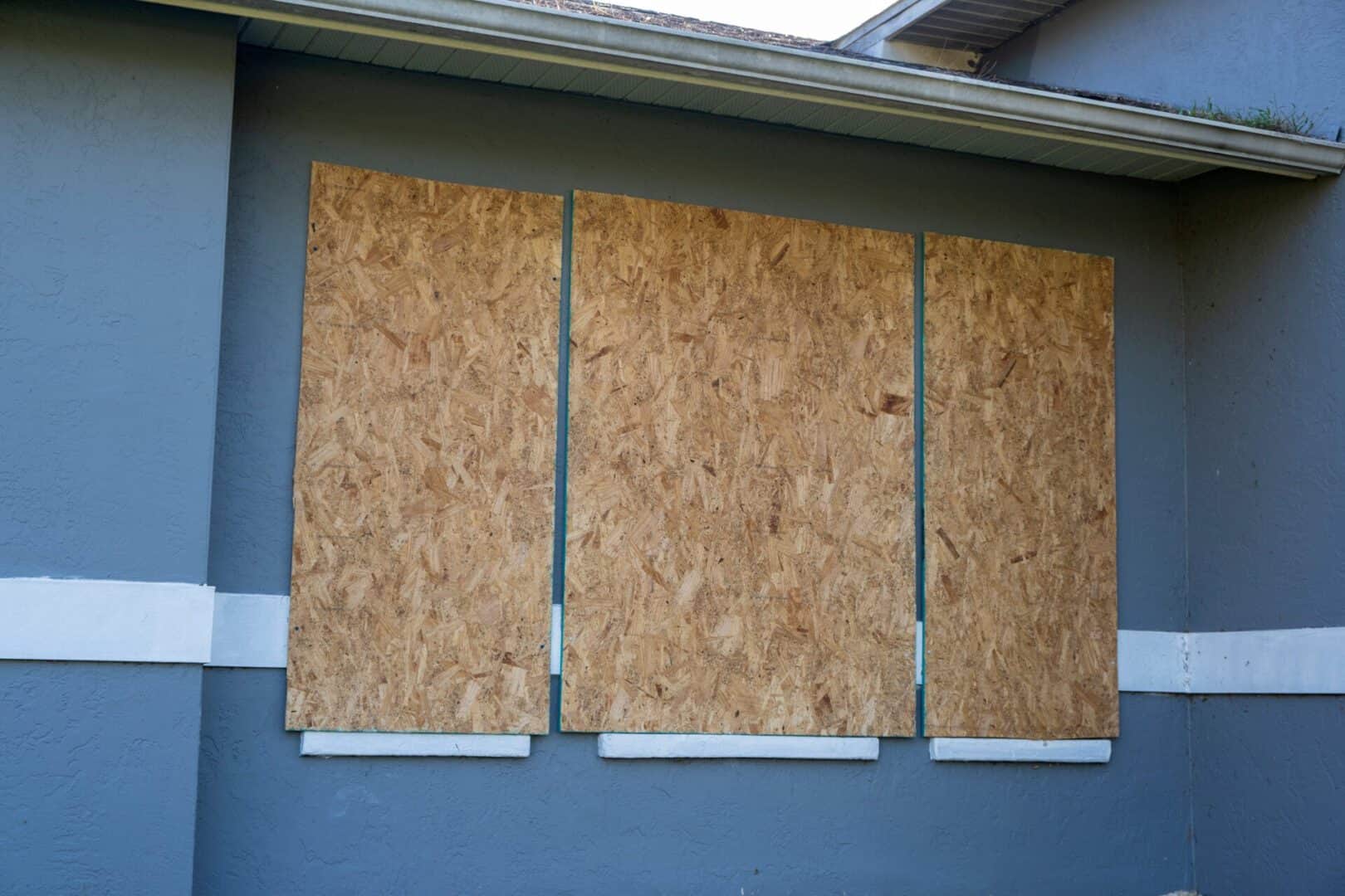 Boarded up windows with plywood storm shutters for hurricane protection of residential house. Protective measures before natural disaster in Florida