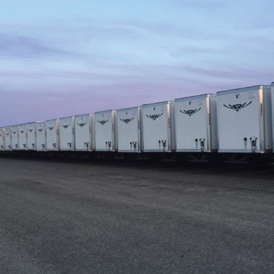Row of white transport trailers at AirportXchange facility under cloudy sky.