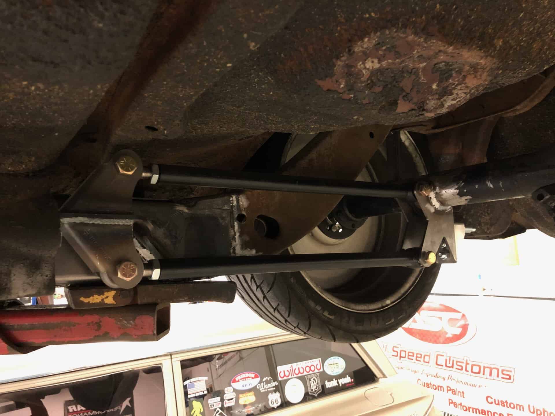 Heavy-duty aftermarket suspension upgrade showing custom subframe connectors and coilovers for improved handling.