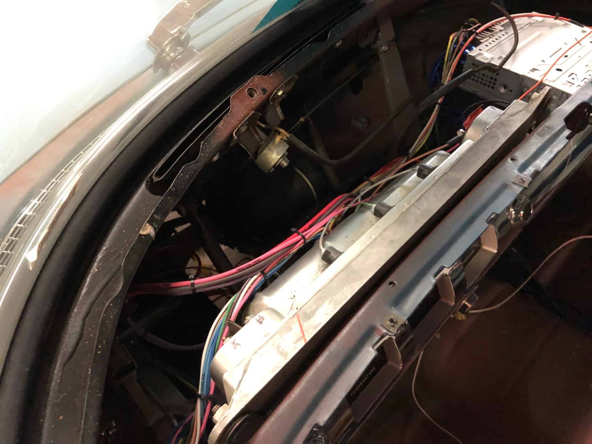Wiring and electronic components inside a custom-car dashboard for performance upgrades.
