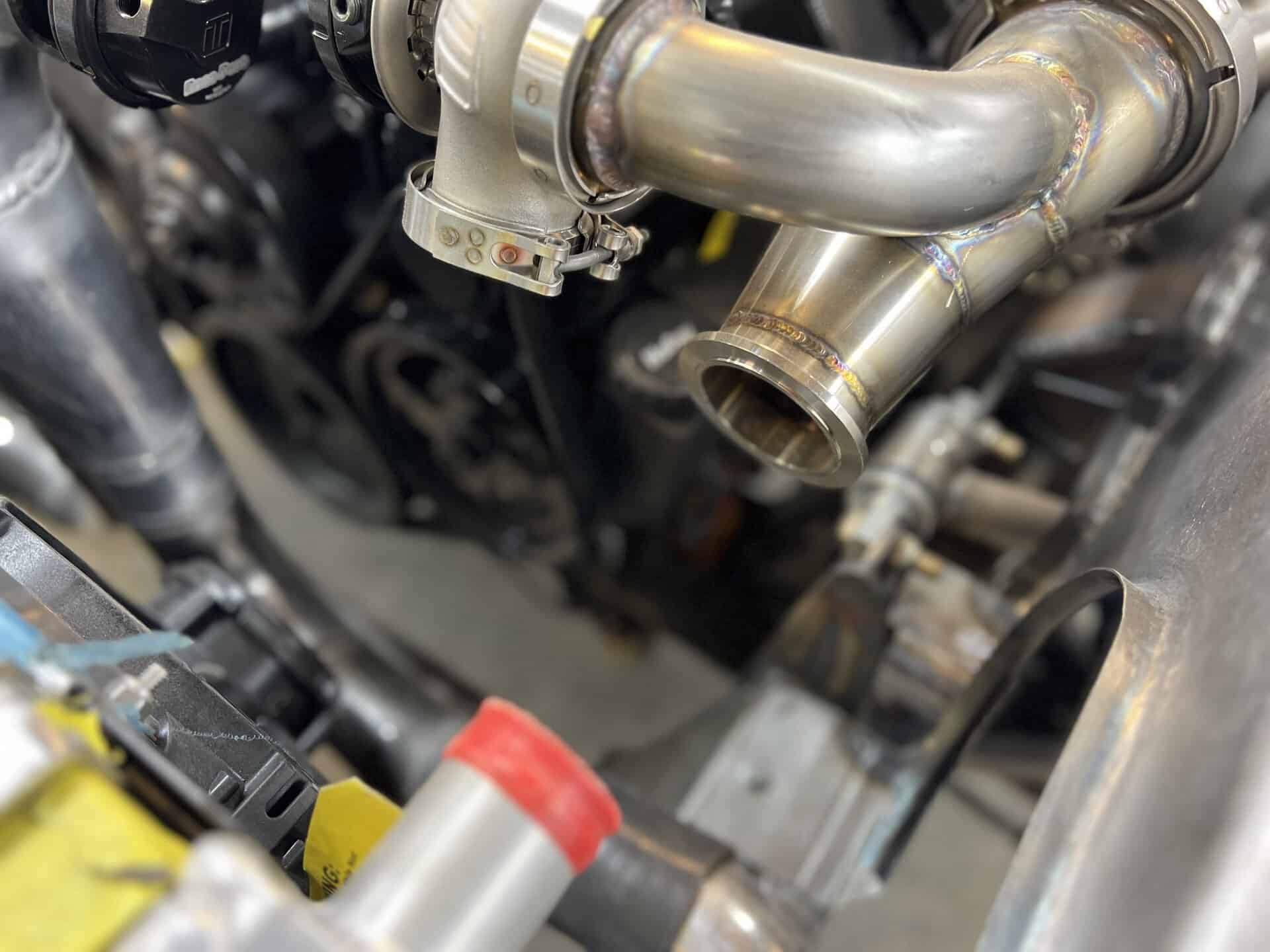 Close-up of custom stainless steel exhaust pipes in a car engine.