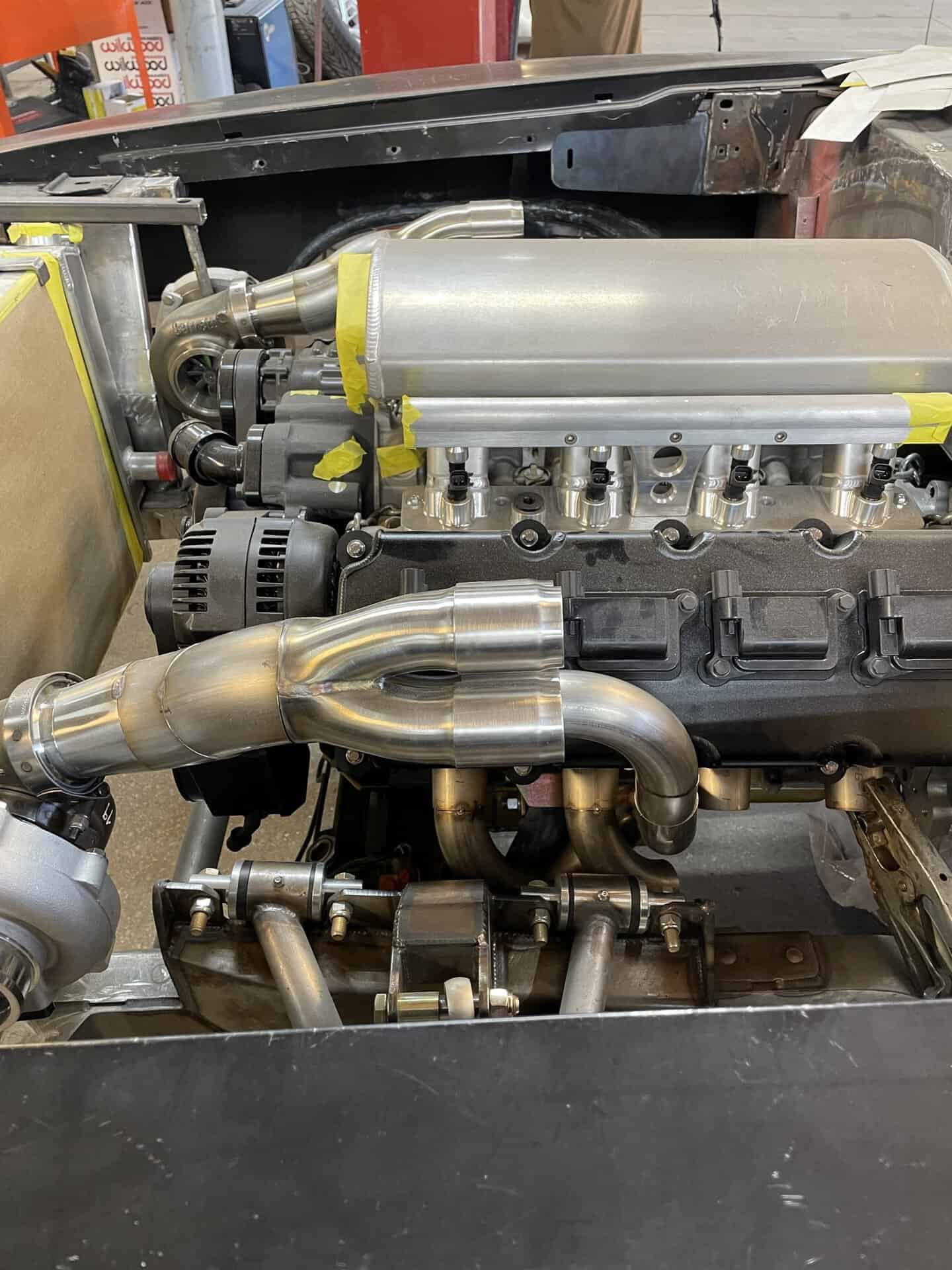 Close-up of a custom car engine with polished exhaust headers and intake manifold.