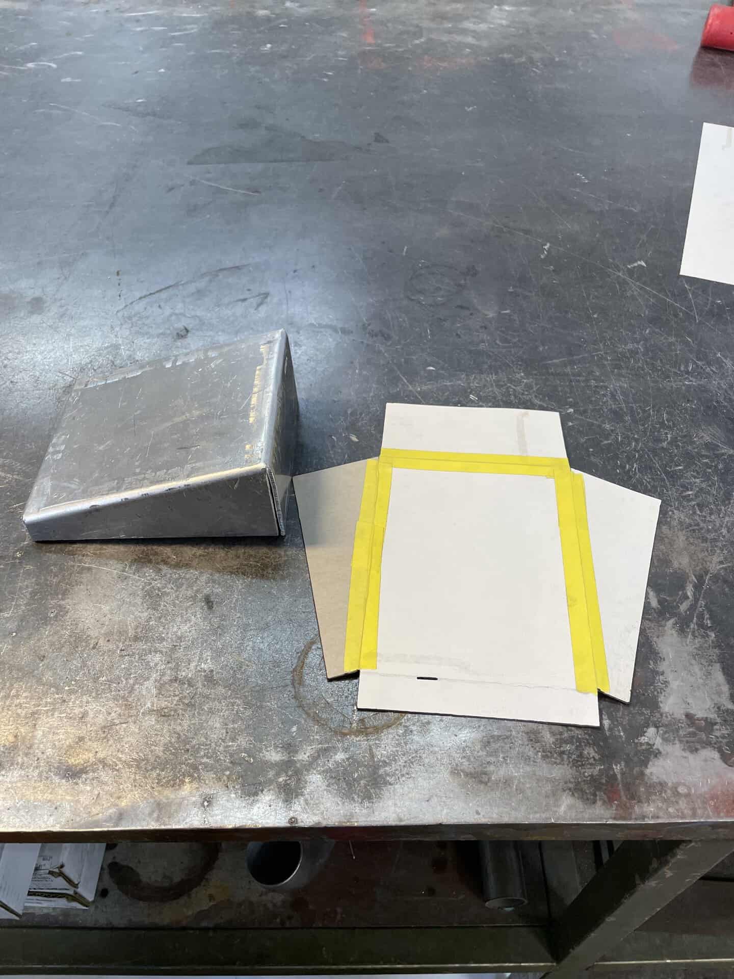 Metal block and paper sheets on a workbench in a workshop.