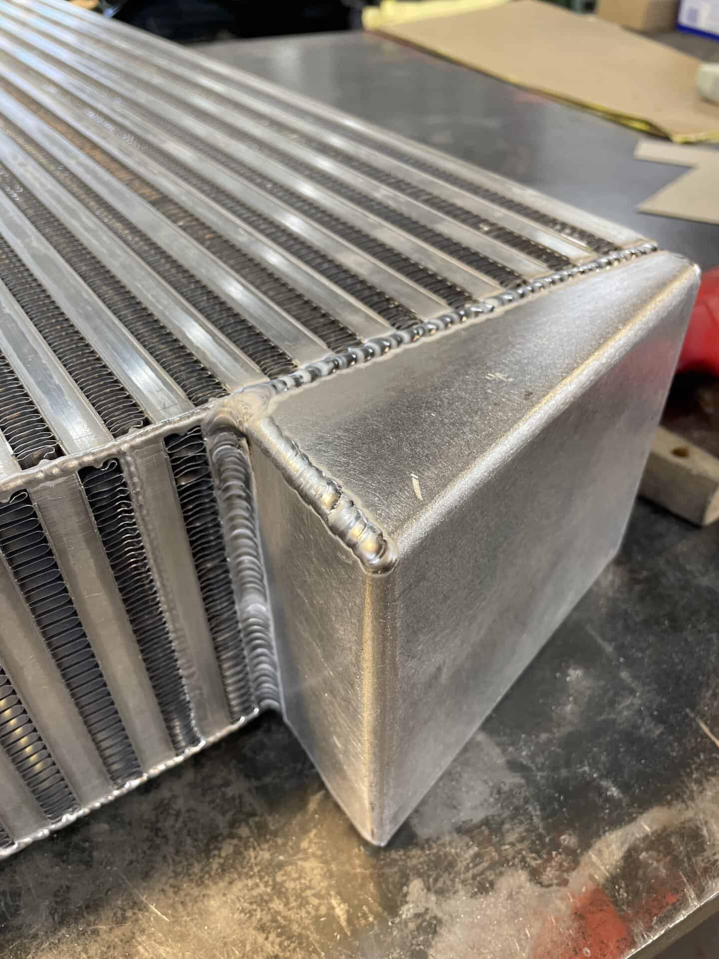 Close-up of a custom aluminum radiator with welded fins and tank.