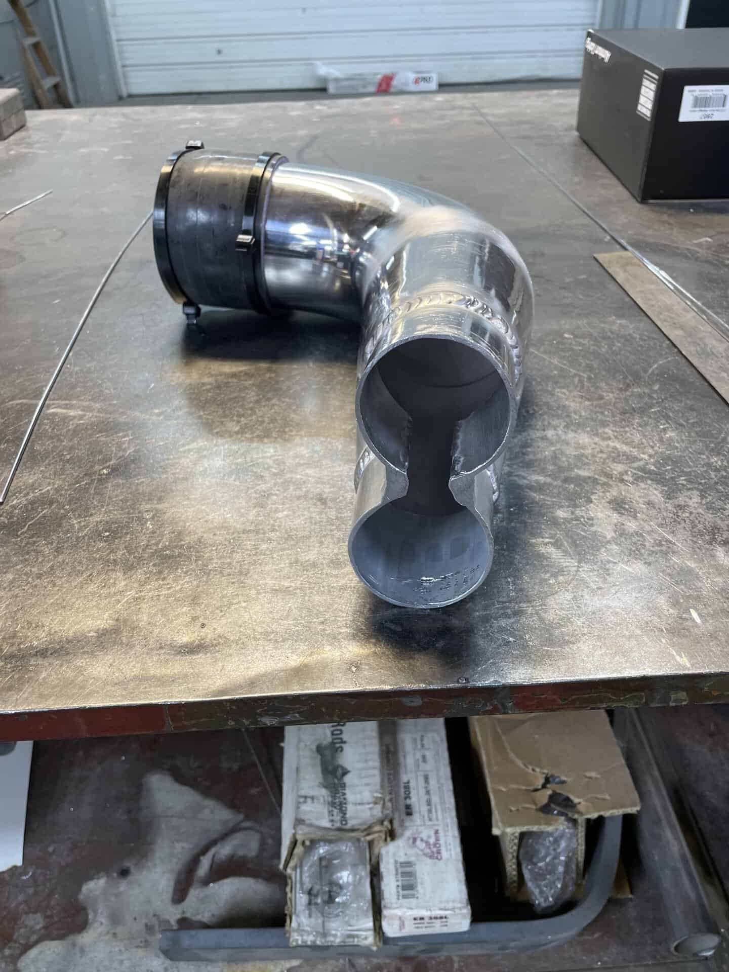 Metal exhaust pipe with a bend and flange for vehicle exhaust system.