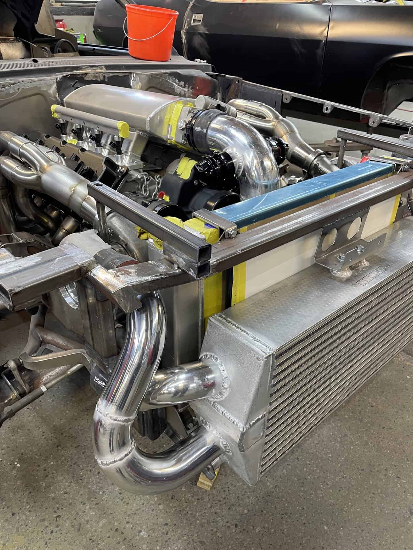 Custom turbocharged engine with polished pipes in a car build.