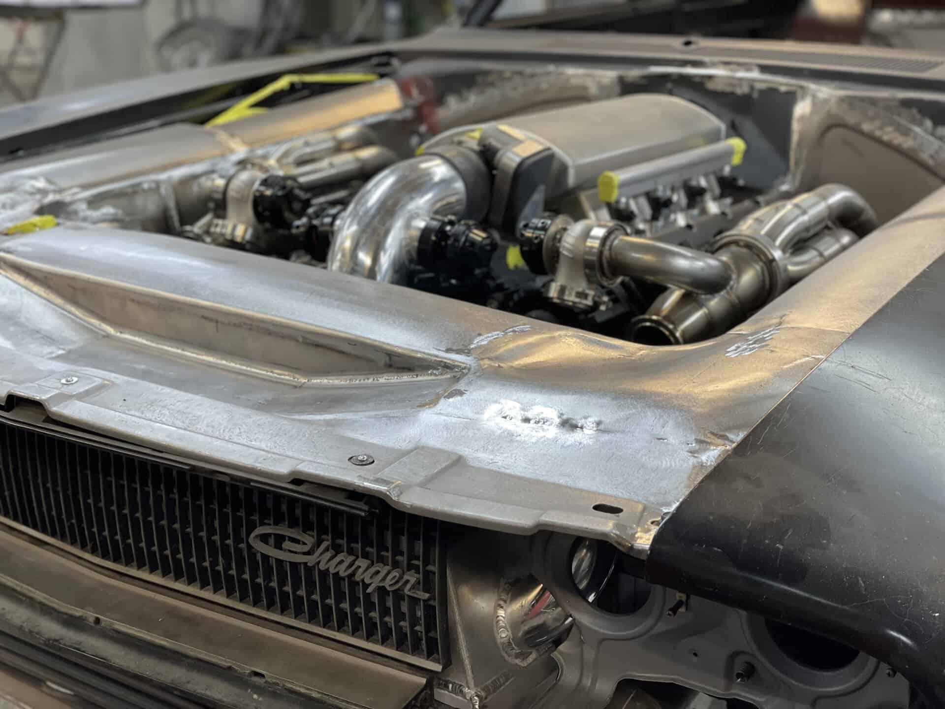 Modified Dodge Charger engine bay with performance parts and custom metalwork.