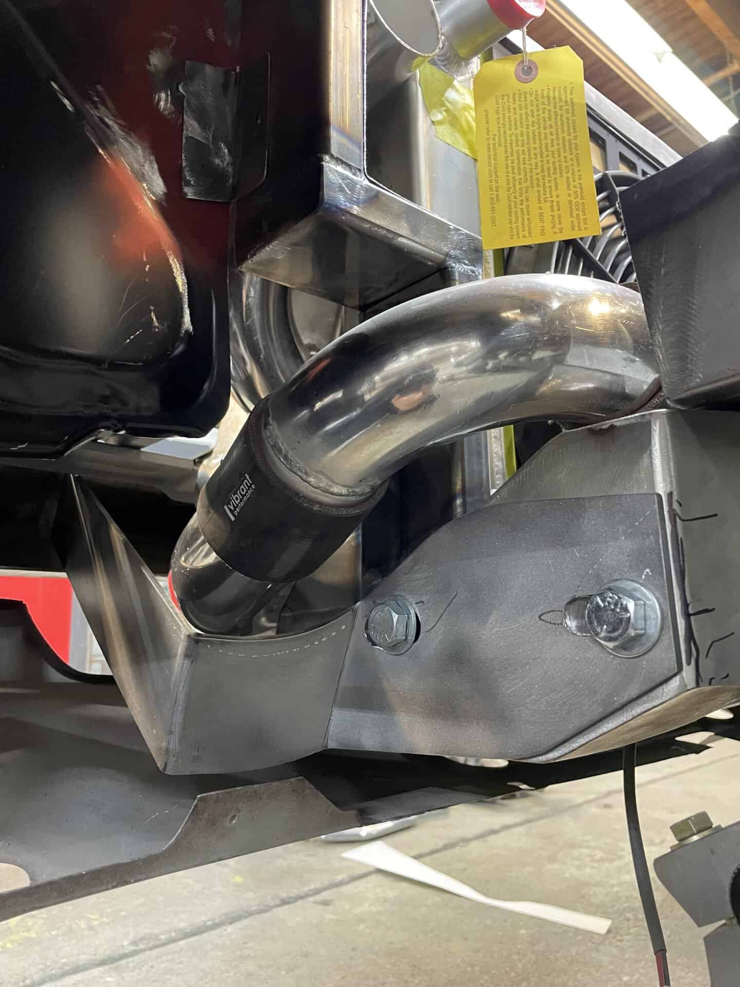 Close-up of custom exhaust pipe and mounting hardware on a classic car.