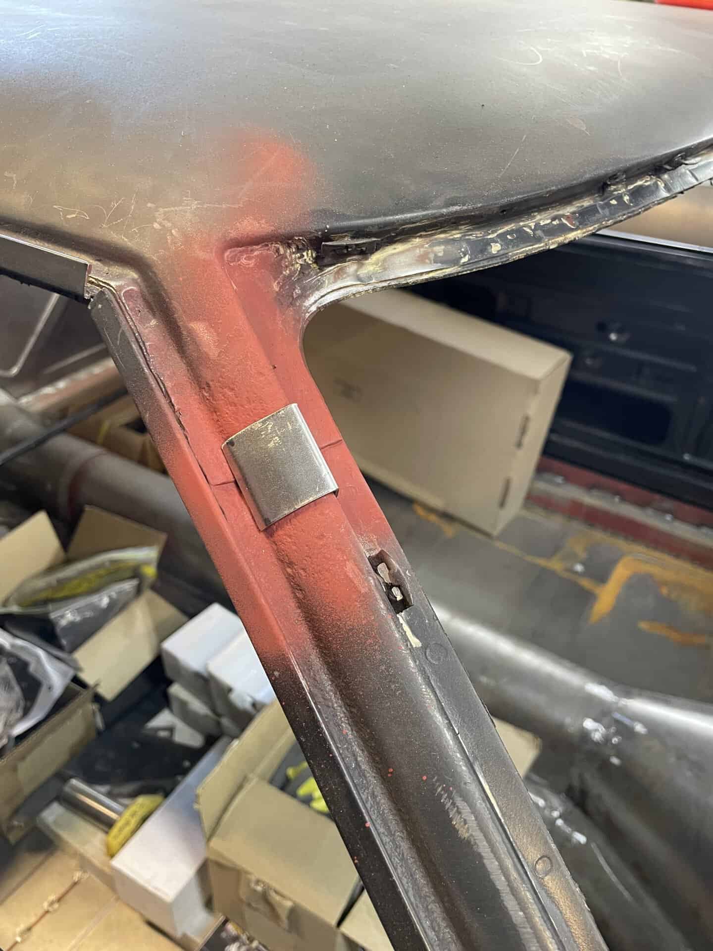 Close-up of car roof restoration showing metal work and primer.
