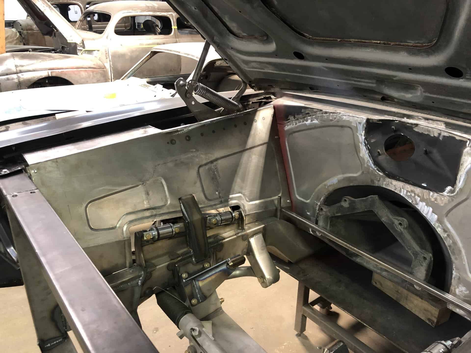 View of engine bay with metalwork and suspension components in progress.