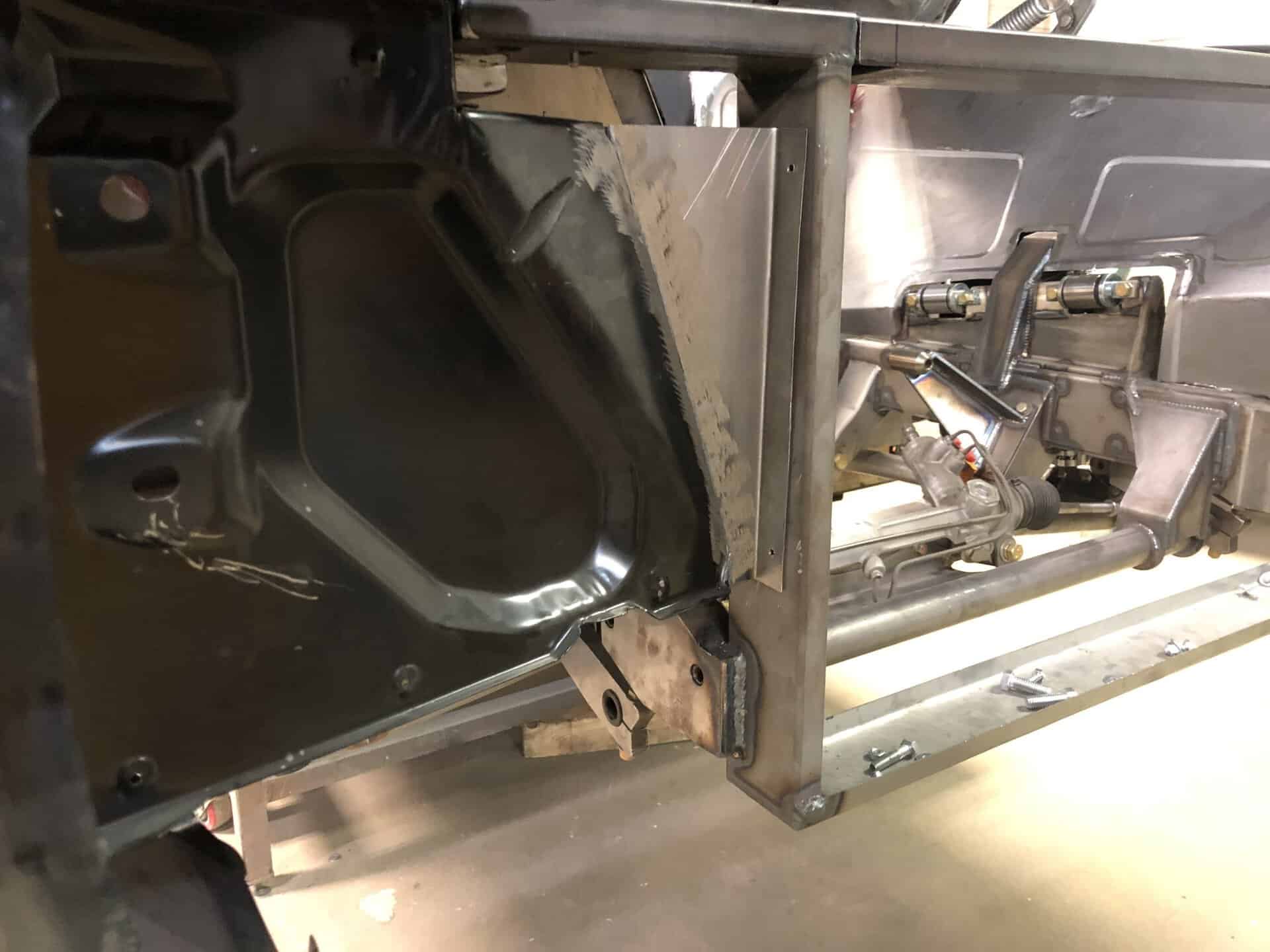 Close-up of car chassis and engine components at All Speed Customs workshop.
