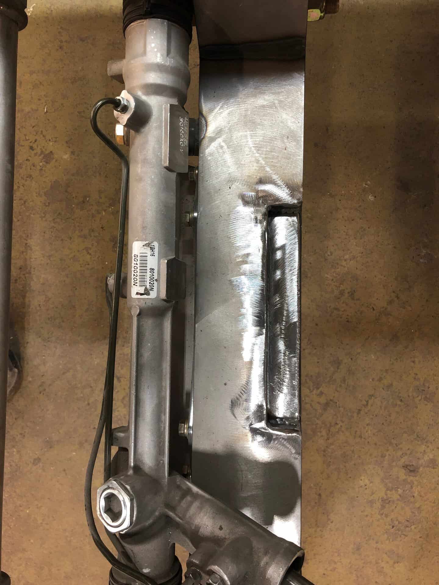 Metal automotive component with wiring and welded parts.