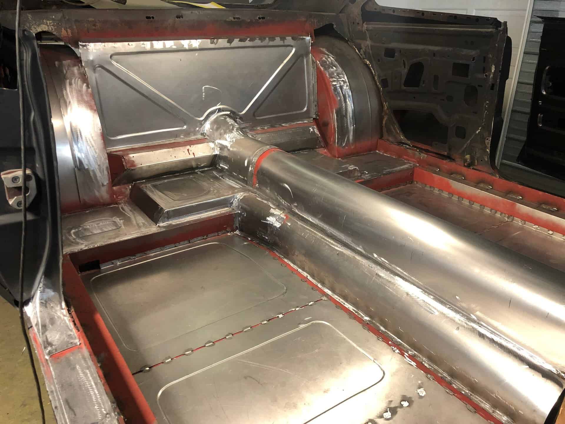 Custom exhaust pipe and metalwork inside a car chassis.