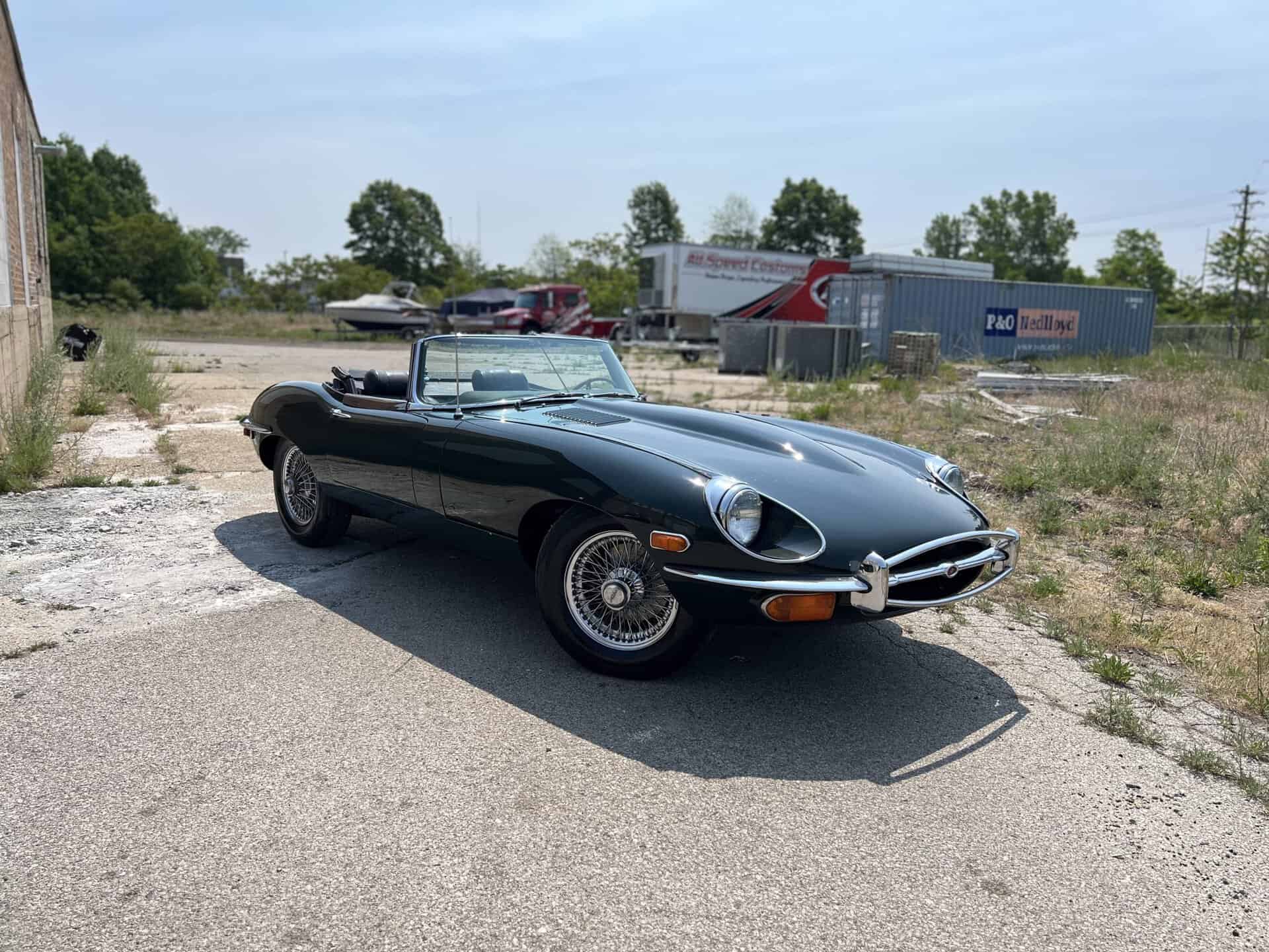 Black 1970 Jaguar E-Type convertible parked outdoors on a sunny day.