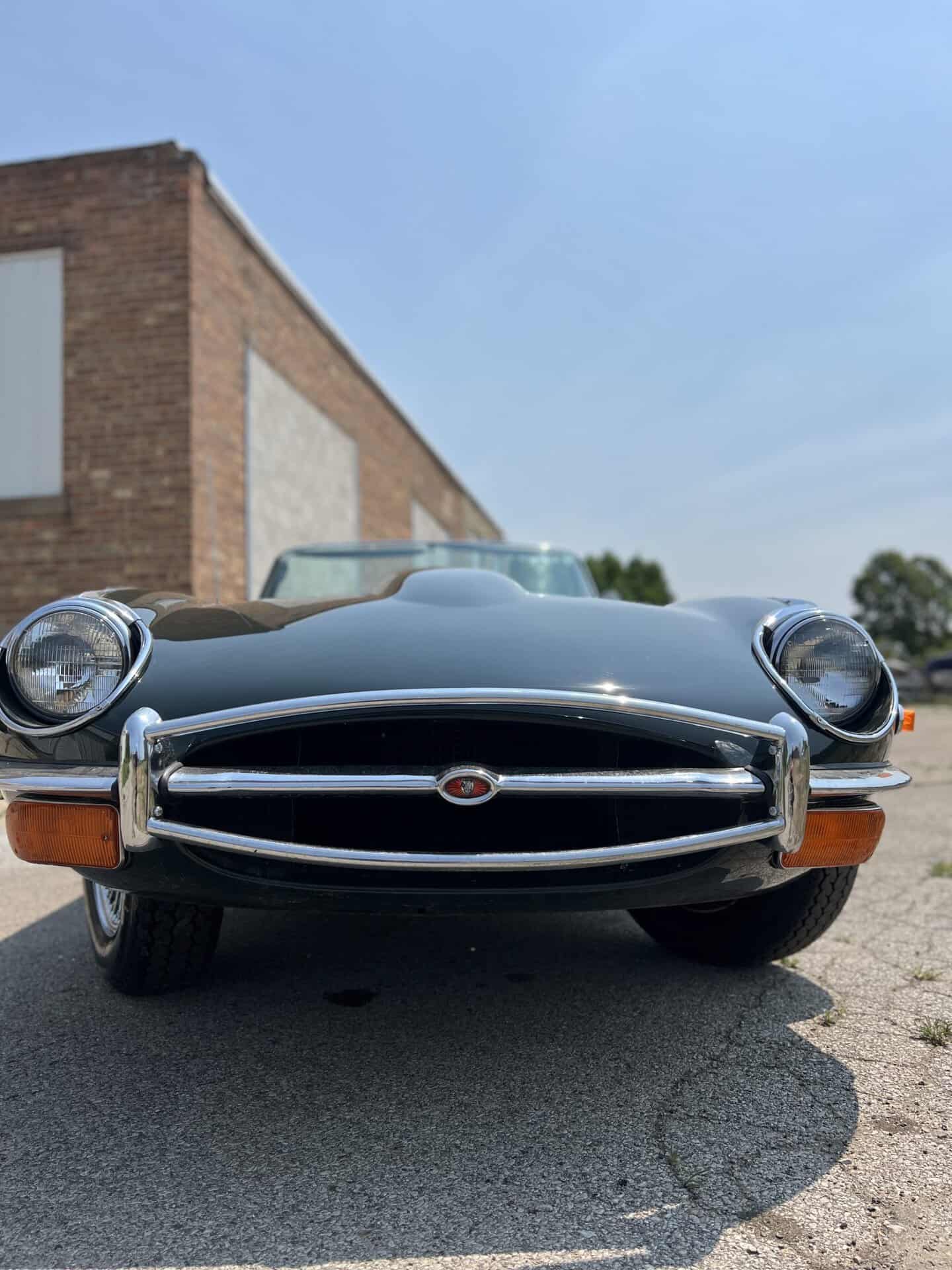 Front view of a vintage Jaguar E-Type with sleek gray body and chrome details.