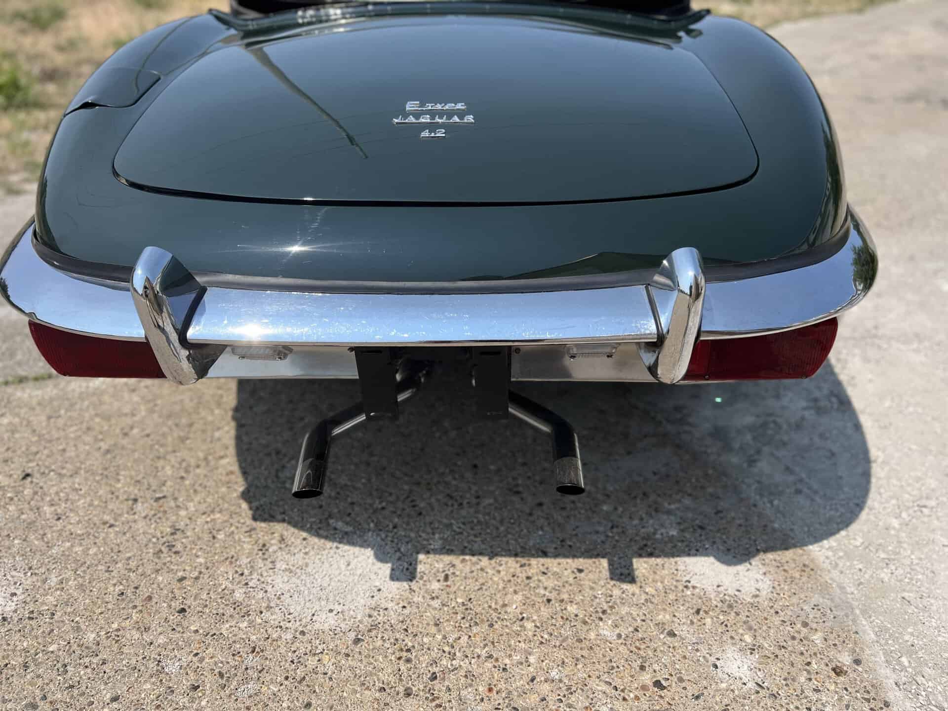 Rear view of a classic 1970 Jaguar E-Type with black paint and chrome bumper.