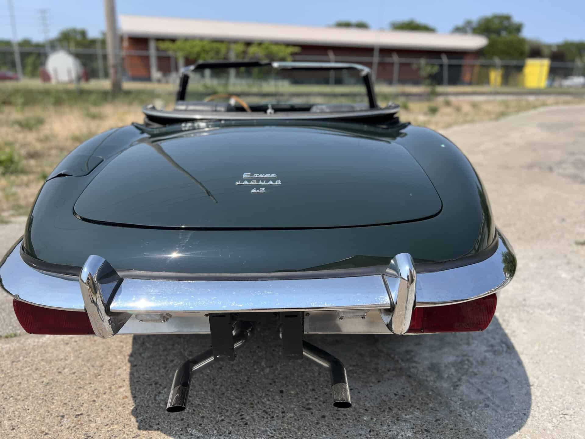 Rear view of a vintage 1970 Jaguar E-Type with chrome bumper and convertible top.