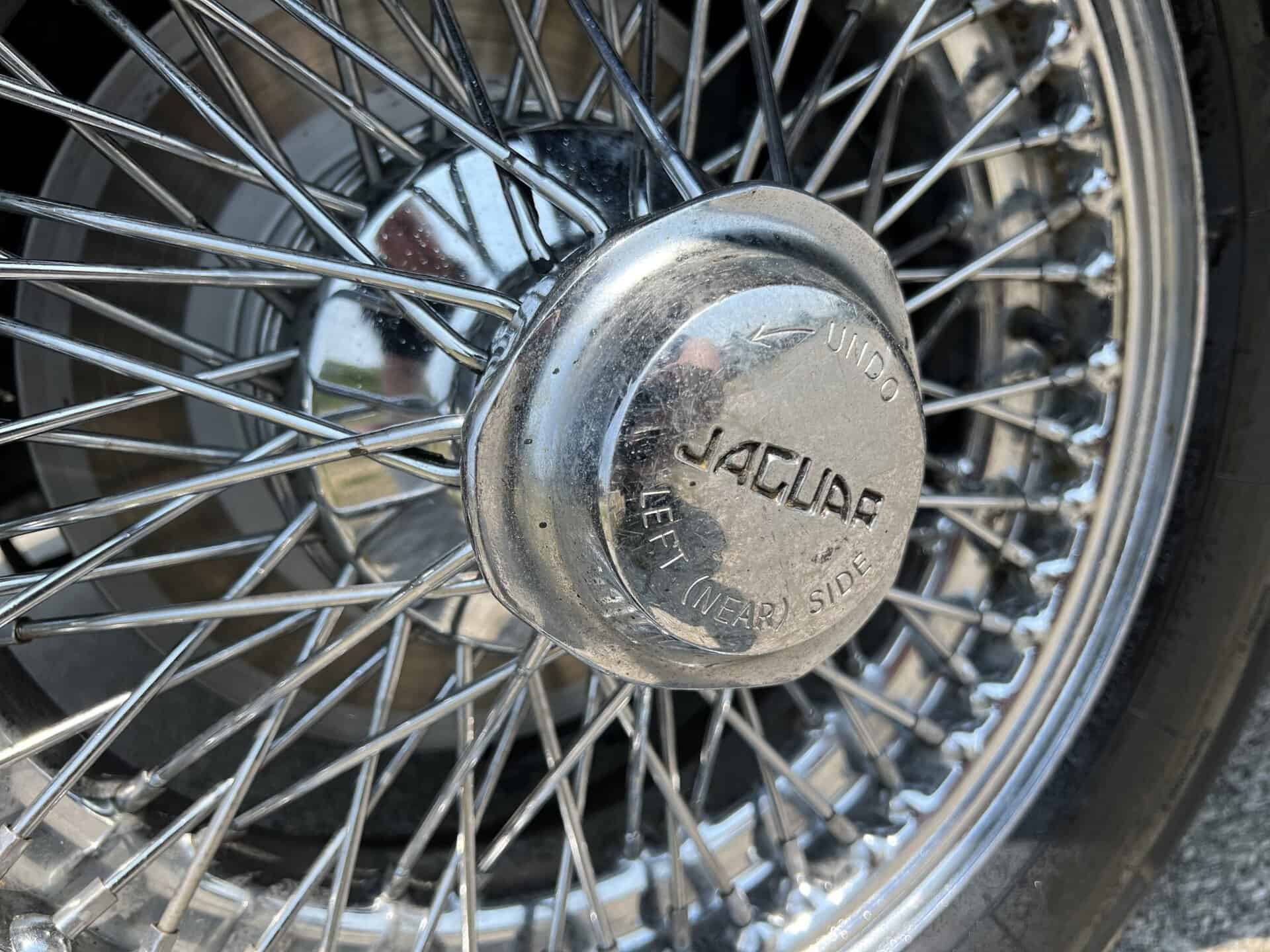 Close-up of Jaguar E-Type wire wheel and hubcap with Jaguar logo.