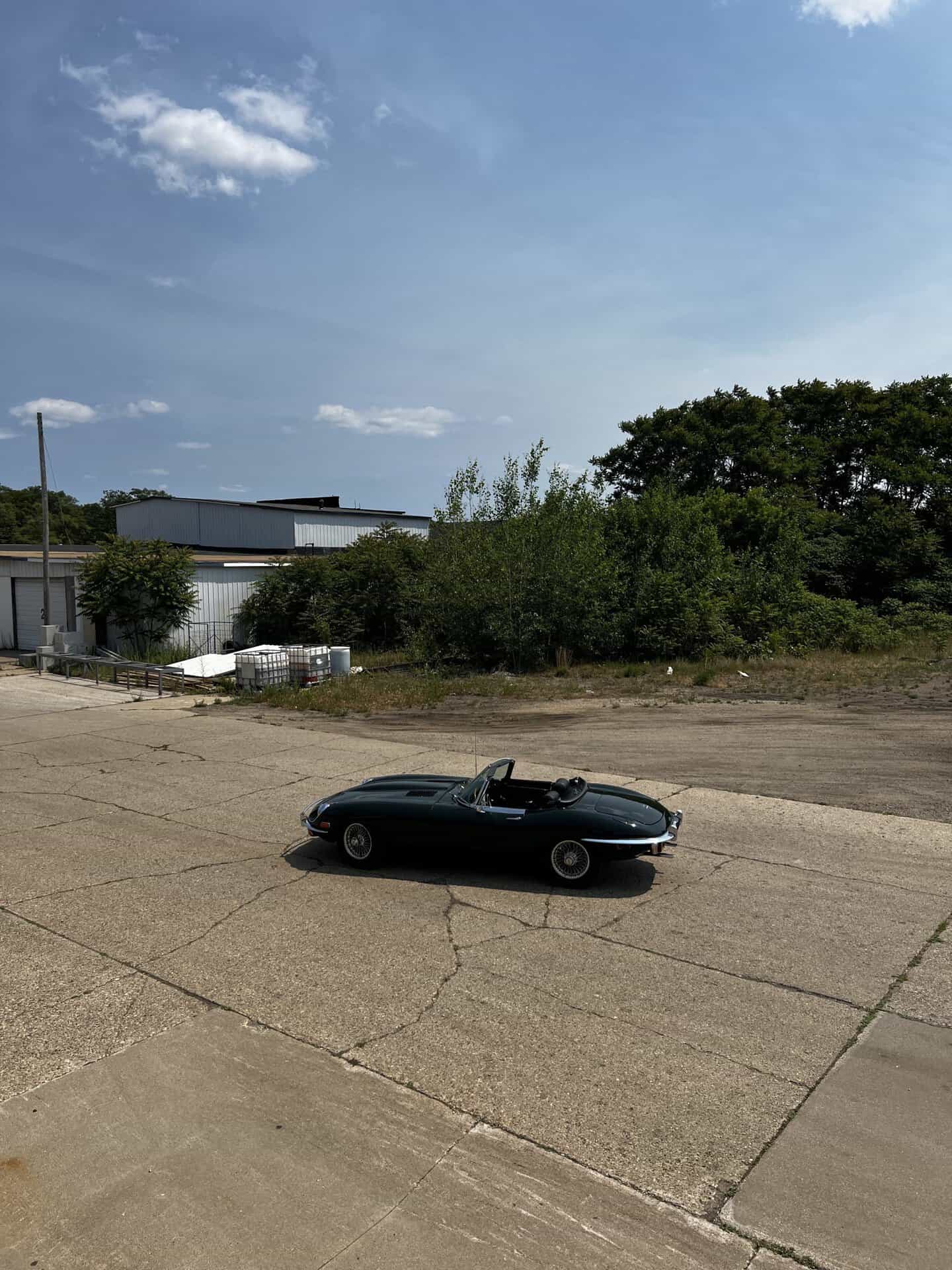 Black 1970 Jaguar E-Type convertible parked outdoors on a sunny day.