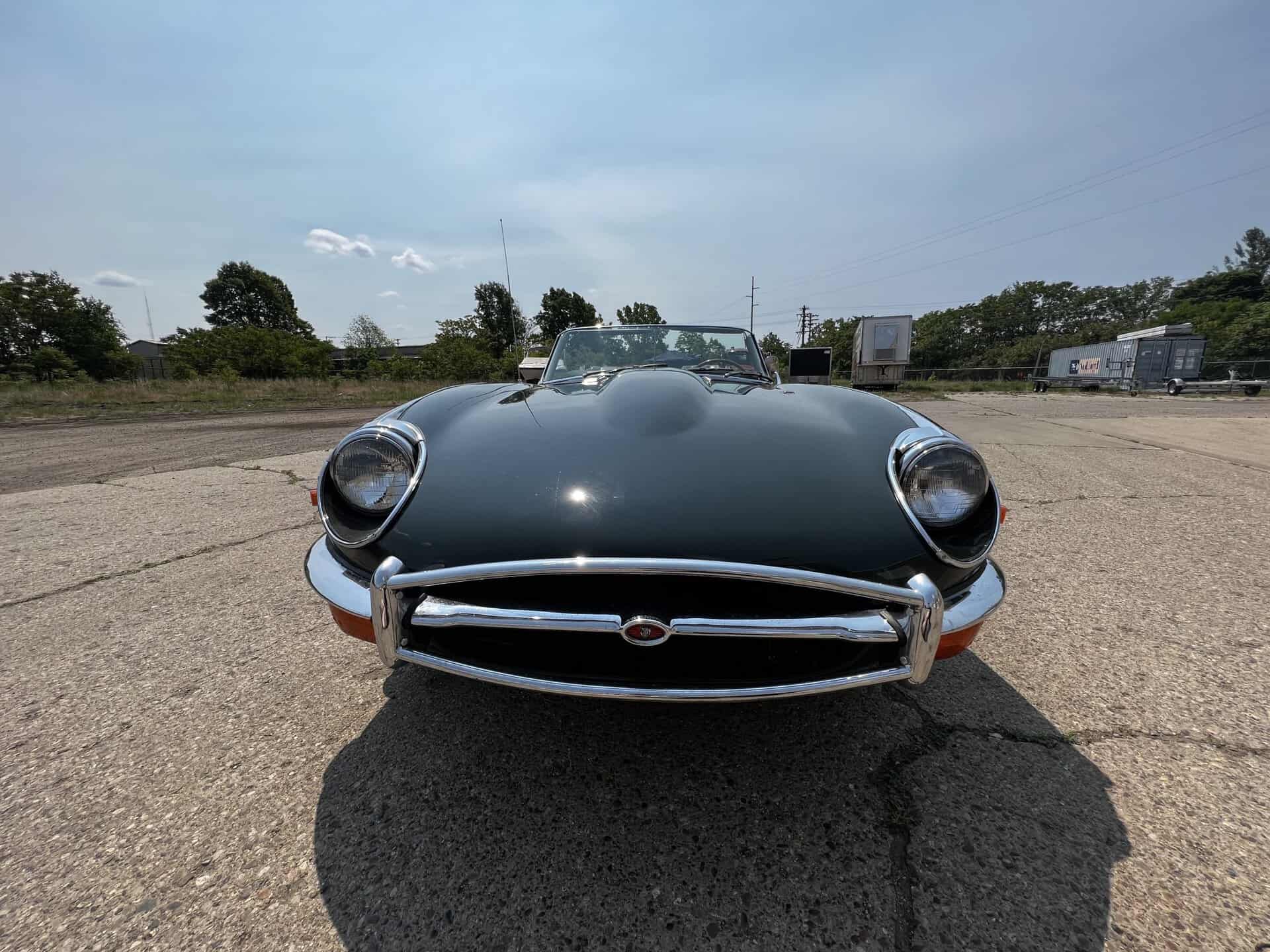 Front view of a 1970 Jaguar E-Type sports car in an open lot.