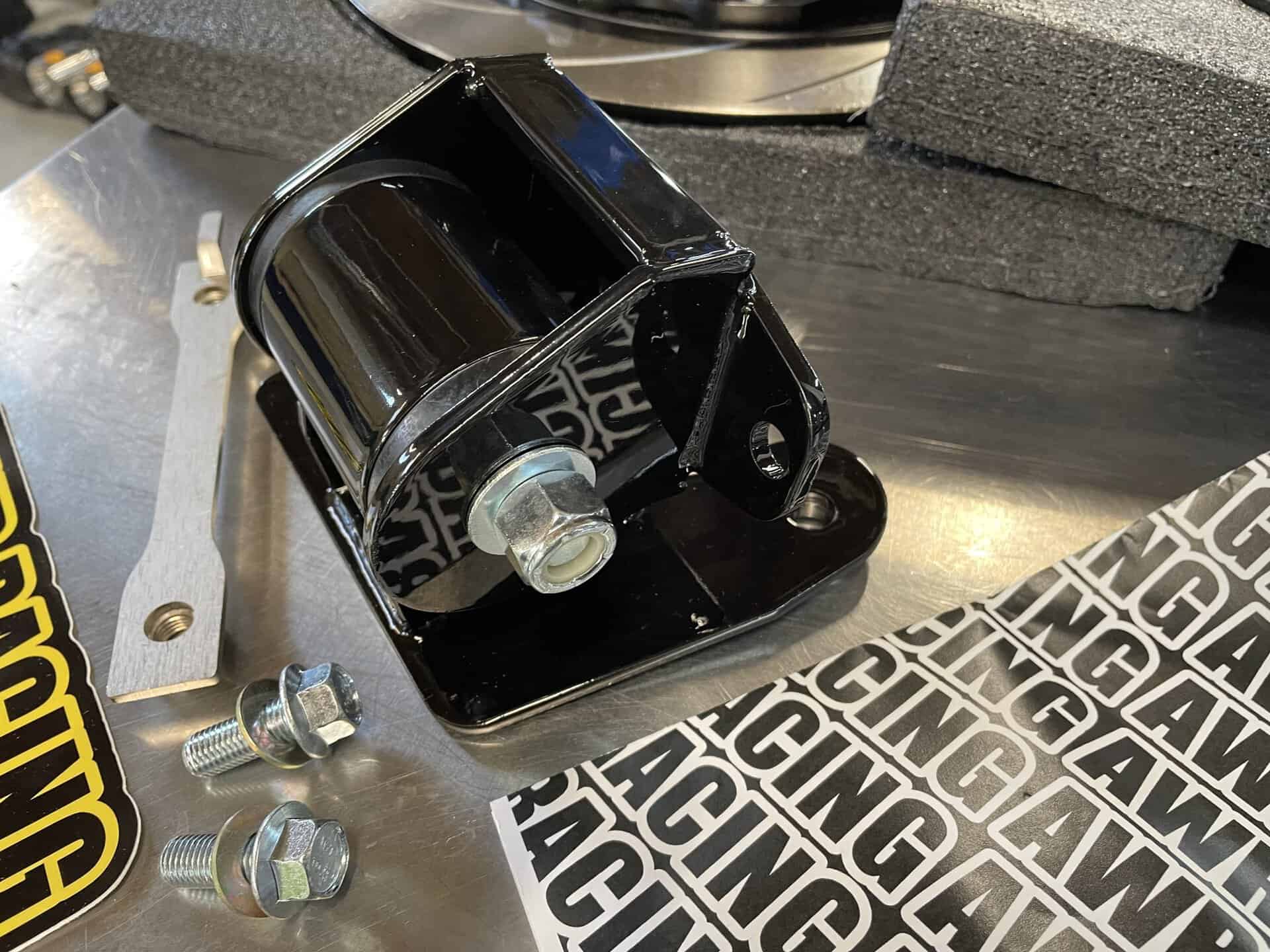 Black motor mount with bolts for vehicle installation.