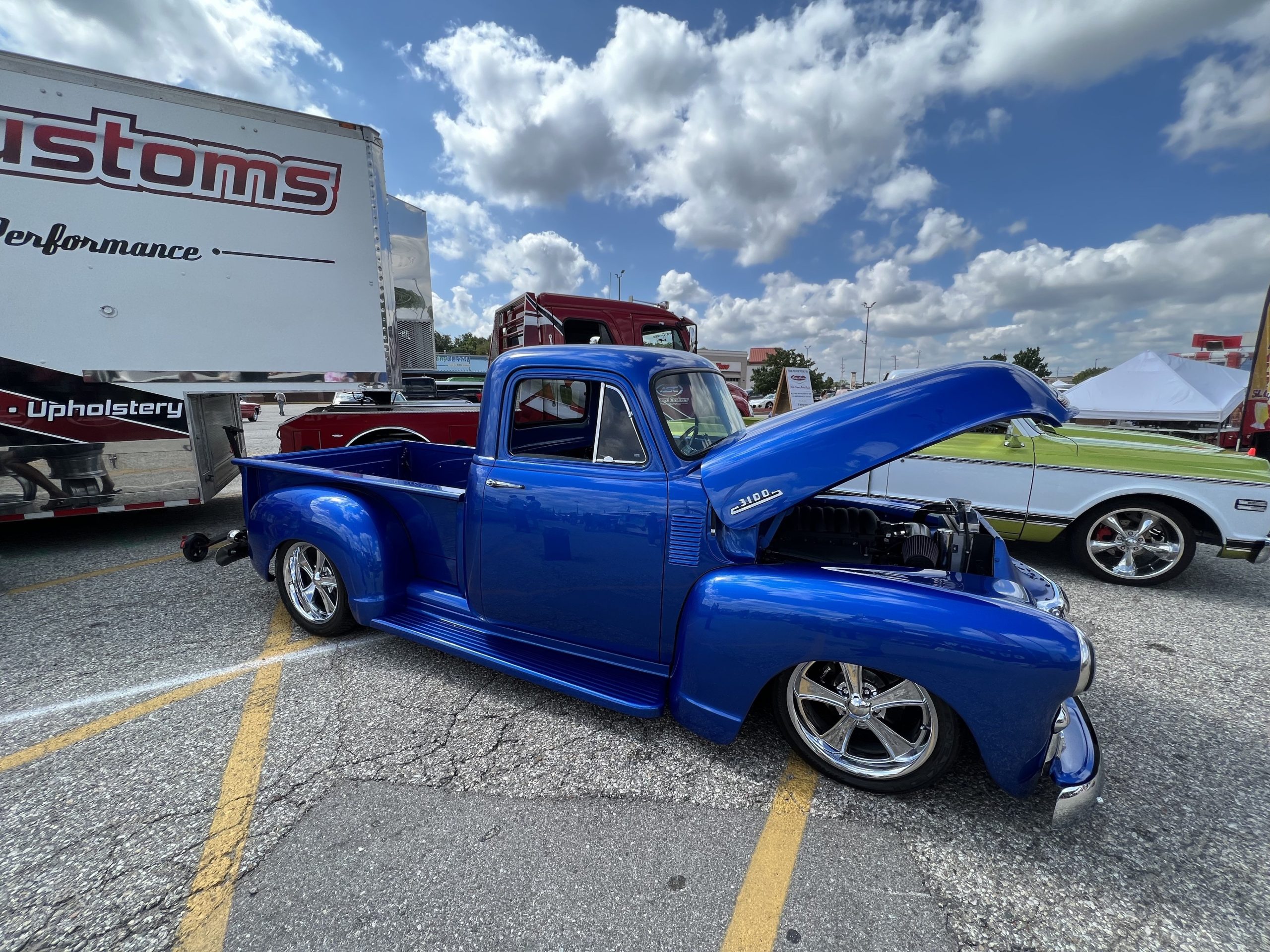 Blue custom vintage pickup truck with open hood at car event.