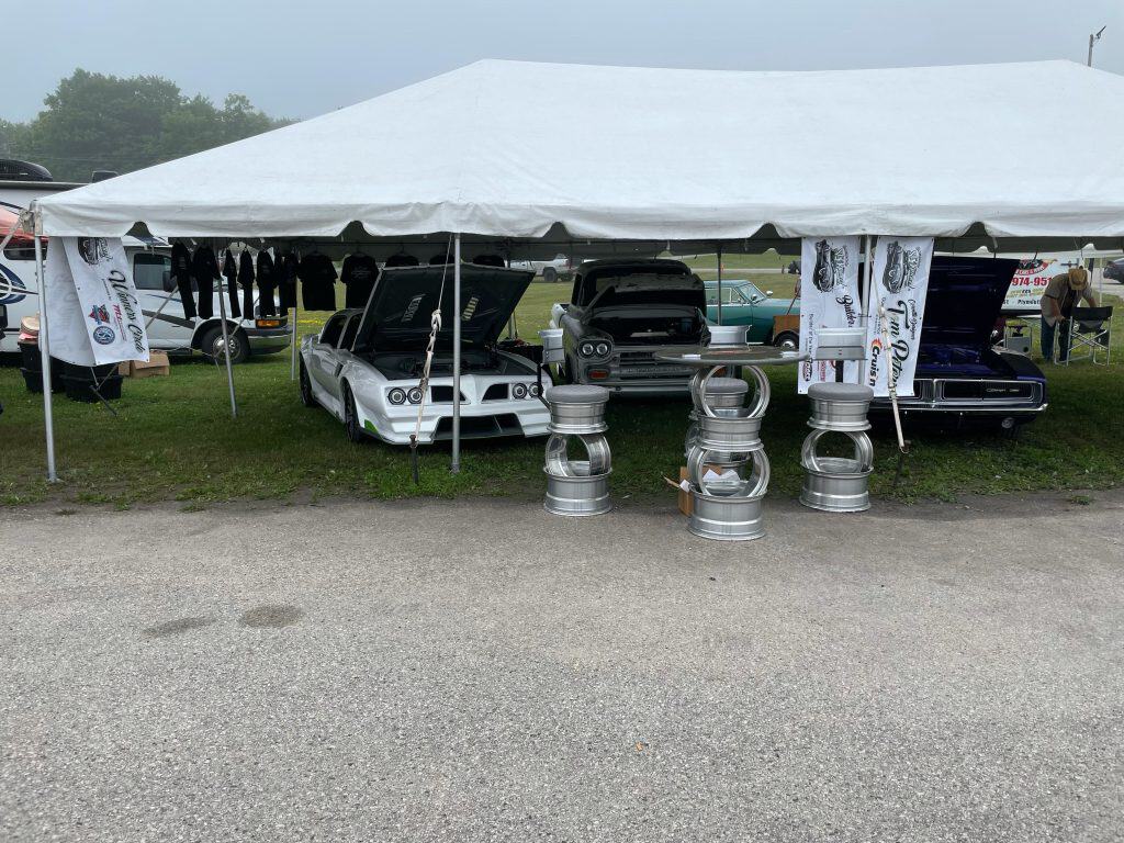 Vintage cars displayed at the 45th St. Ignace Car Show under a white tent.