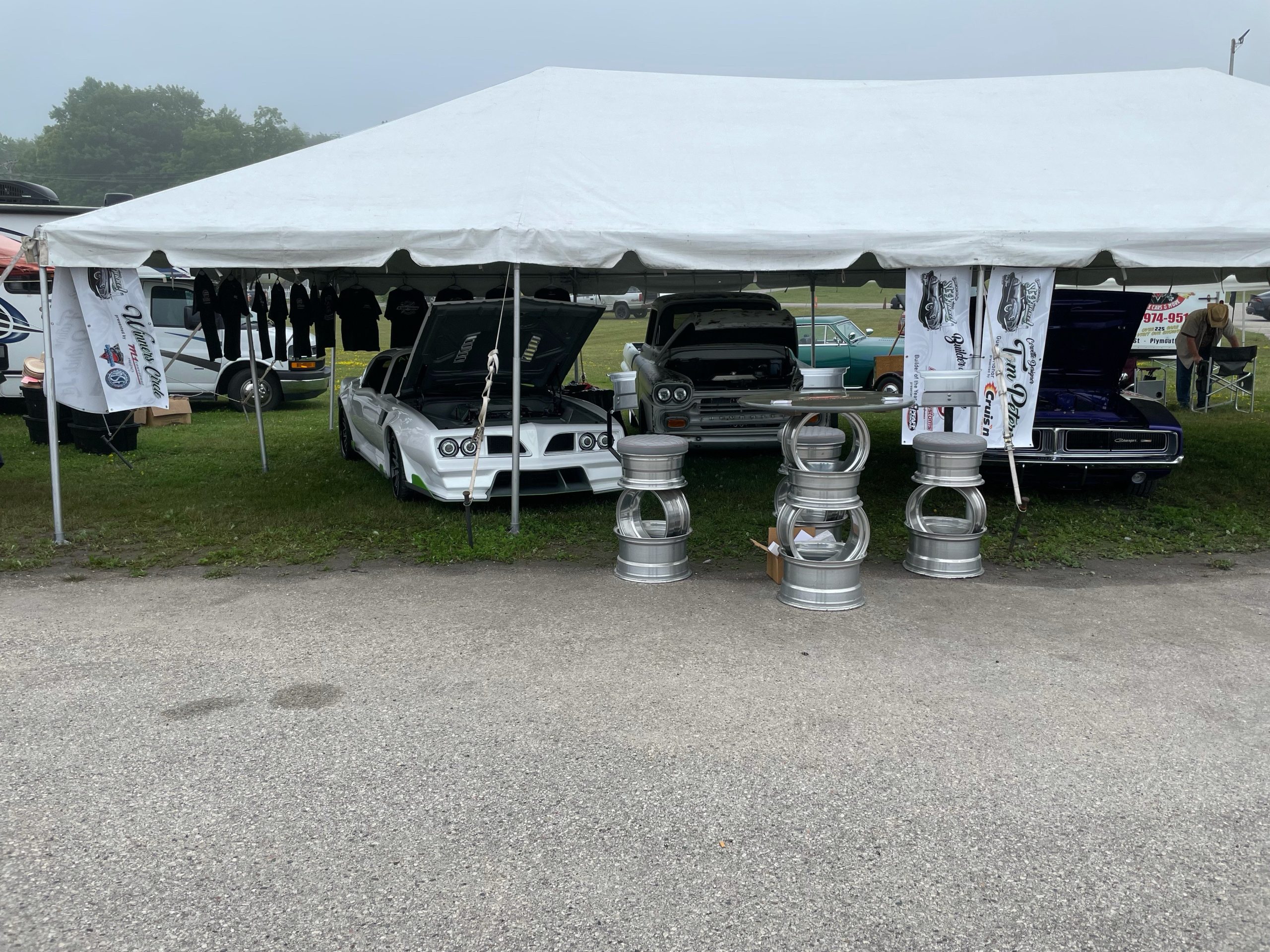 Vintage cars displayed at the 45th St. Ignace Car Show under a white tent.