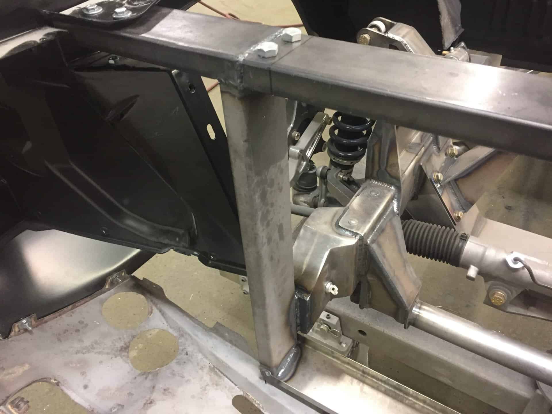 Close-up of custom car frame and suspension parts in workshop.